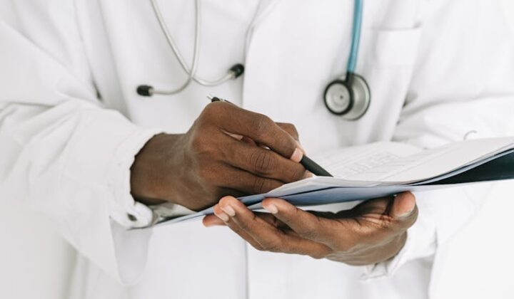 Doctor Holding Pen Writing on Paper